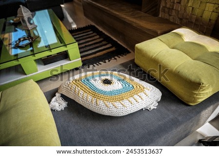 Detail of modern interior design in living room.Stylish grey sofa adorned with vibrant green pillows, including one eye-shaped pillow positioned centrally, adding whimsical touch to contemporary decor