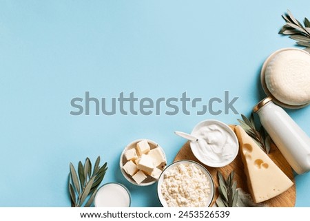 Various dairy products. Milk bottle, cheese, cottage, sour cream, butter on light blue background, top view, copy space. Organic food,  Jewish Shavuot holiday breakfast. Royalty-Free Stock Photo #2453526539