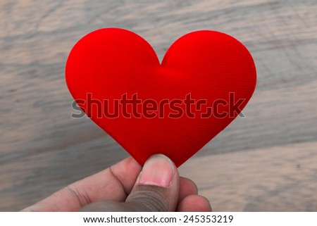 male hand holding fabric red valentine heart.