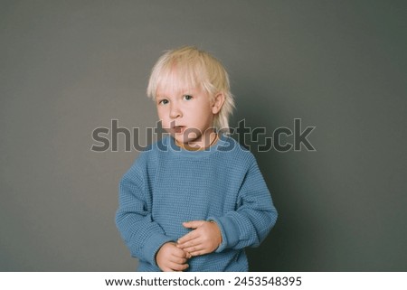 Studio portrait of adorable 4 -5 year old boy posing on grey background