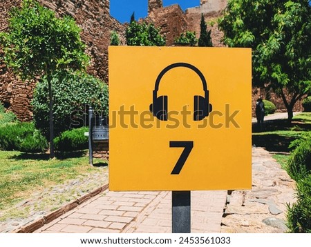 view of a music headphones icon with number 7 in a yellow sign board in the Alcazaba in the City of Malaga, Andalusia, Spain Royalty-Free Stock Photo #2453561033