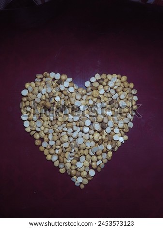 It is a picture of heart shaped roasted chickpea grains isolated on a maroon background.