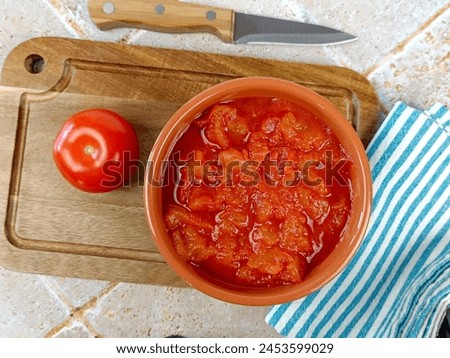bowl of crushed tomatoes, close-up, on a cutting board Royalty-Free Stock Photo #2453599029
