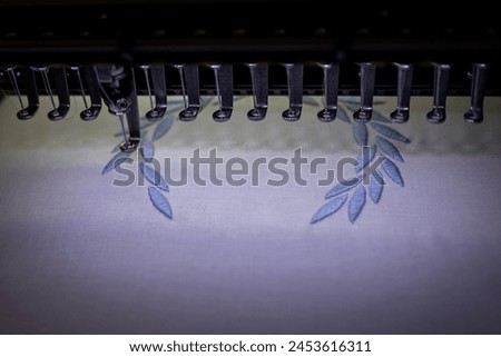 Embroidery design on white fabric with blue thread. Machine embroidery. Close up.