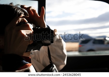 A tourist person taking photo with a DSLR camera inside a car from road trip journey focusing on the picture of nature landscape outside