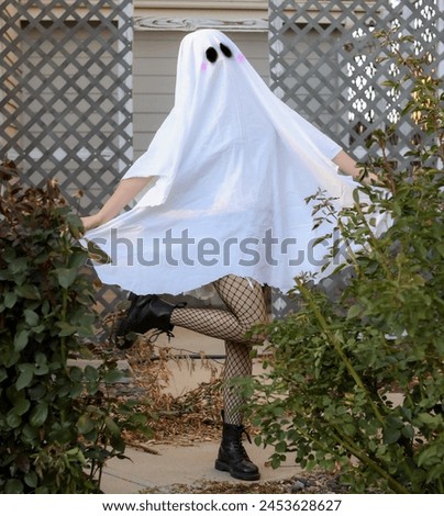 cute kawaii alternative woman dressed up in homemade bedsheet ghost costume for Halloween 