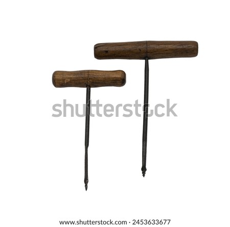 Detail of two old manual punches with wooden handles. They are traditional tools for drilling holes in wood and starting threads. They are on a white background Royalty-Free Stock Photo #2453633677