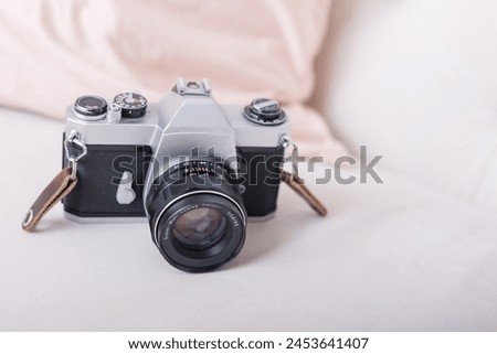 Old time film camera on a white couch with pink pillow