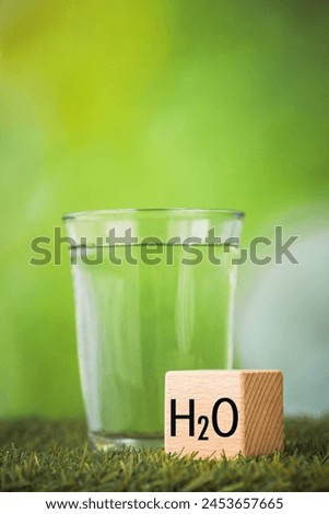 h2o water, Impact of water on the environment, Environmental science concept, Glass of water on green background, wooden block with h2o symbol, Vertical