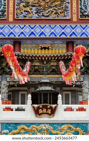 A building with red lanterns hanging from the roof. The lanterns are decorated with Chinese characters and are lit up, creating a festive and lively atmosphere