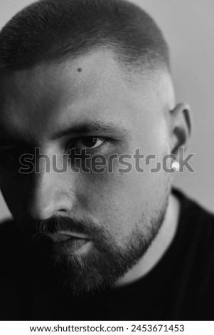 Portraits of a Millennial guy with a short haircut and beard, earrings in his ears
