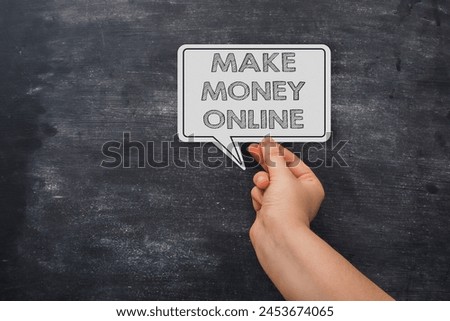 A hand holding a white sign that says Make Money Online. The sign is on a black background