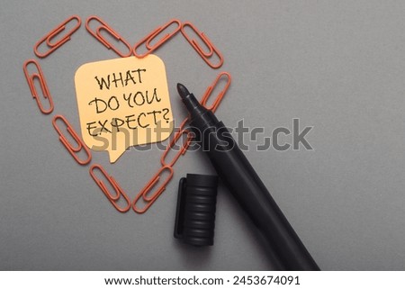 A pen is on a piece of paper with a heart shape and the words What do you expect written on it Royalty-Free Stock Photo #2453674091