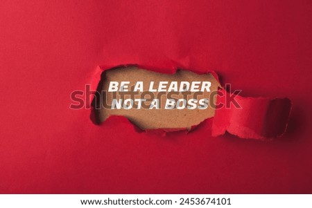 A red background with a hole in it and the words be a leader not a boss written in white