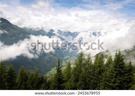 The sun shines after a huge rain storm and clouds begin to scatter revealing the lush green valley floor, Hohe Tauern National Park, Osttirol, Austria Royalty-Free Stock Photo #2453678955