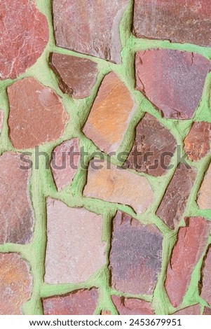 It is the photo of colorful stones on green background. Its close up of multicolored stone wall of building. It is photo of mosaic tile floor