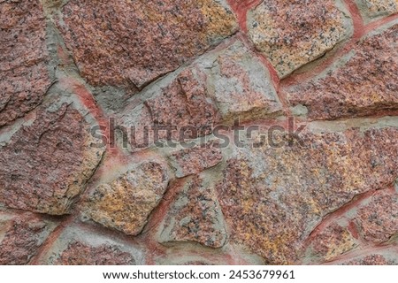 It's close up view of red and yellow stones of wall. This is photo of pink stone wall of building. It is view of colorful stone wall of castle. It is view of stone wall texture.
