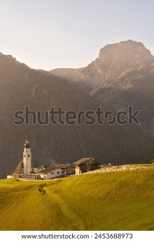 A small church shining in beautiful golden autumn light, Lienz Dolomites, Pustertal (Puster Valley), Osttirol, Austria Royalty-Free Stock Photo #2453688973