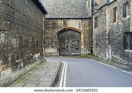 Old medieval alley in England with stone building and wooden gate Royalty-Free Stock Photo #2453689201