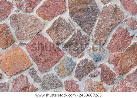 It's close up view of colorful wall. Its photo of multicolor stonewall. It is photo of multicolored srone wall. its the view of red sidewalk. It's view of mosaic color stones