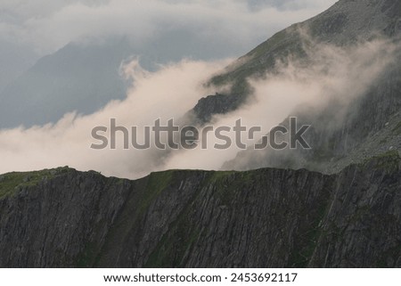 Clouds and fog surrounding a mountain ridge with a dizzying path zig-zagging over the ridge, Hohe Tauern National Park, Osttirol, Austria Royalty-Free Stock Photo #2453692117