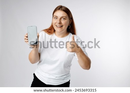 Photo of positive confident woman holding modern device and showing thumb up isolated white background. 30s girl showing blank screen mobile phone
