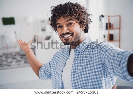 Photo of cheerful positive guy dressed plaid shirt tacking selfie enjoying weekend inviting you indoors room home house