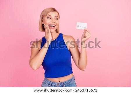 Photo of pretty young woman look debit card empty space wear blue top isolated on pink color background