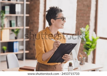 Photo of lovely mature lady look window sign report dressed yellow formalwear modern workplace success business owner home office