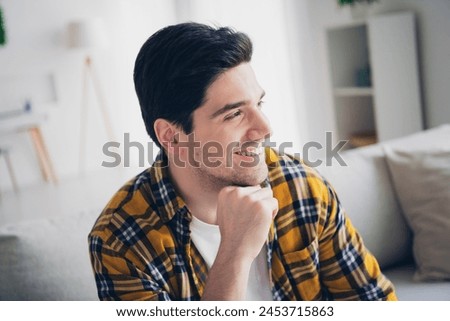 Photo of dreamy positive guy dressed plaid shirt arm chin relaxing sofa enjoying weekend indoors room home house Royalty-Free Stock Photo #2453715863