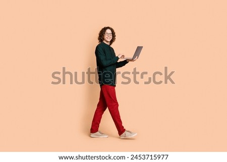 Photo portrait of handsome young guy eyewear hold netbook walk dressed stylish green garment isolated on beige color background