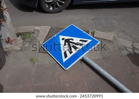a pedestrian crossing sign lies on the roadway