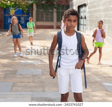 Portrait of smiling schoolboy walking on the street, kids on background