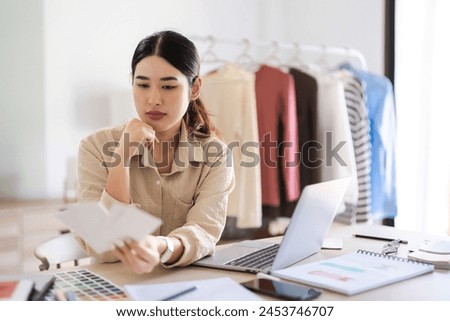 Fashion designer women looking on color swatch sample to design clothes for creative new collection.
