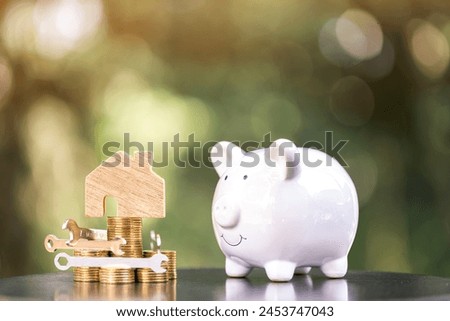 Home model and construction tools with repairing put on the stack gold coin and piggy bank put on the wood in the public park, Saving money and loan for renovation to real estate and house concept.