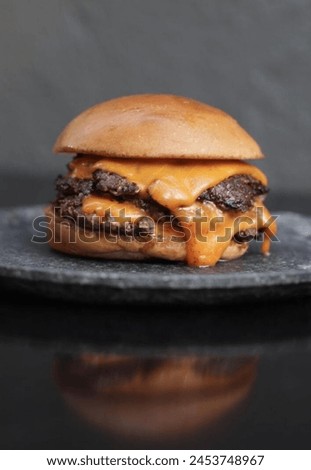 Indulge in the ultimate comfort food - a juicy cheeseburger perfectly plated on a sleek black dish.