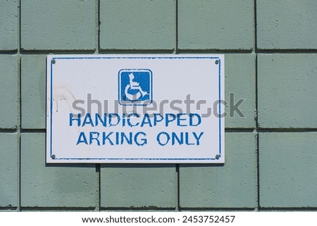 An image of a very old handicapped parking sign which is faded and peeling. 