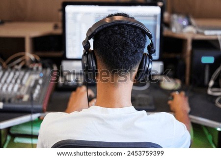 DJ, computer and man in recording studio for music producer with tech and headphones. Sound engineer, audio technician or back of media editor in professional radio booth with synthesizer control
