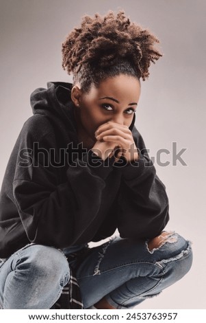 Playful yet poised, young female in casual wear engages viewers Royalty-Free Stock Photo #2453763957