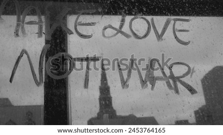 'make love not war' lettering on a window, church background and a sky