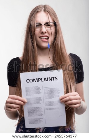 Focused professional analyzes complaints with a critical eye, pen in mouth Royalty-Free Stock Photo #2453764377