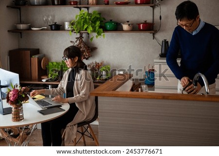 Wife works from home, husband does housework Royalty-Free Stock Photo #2453776671