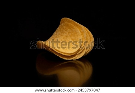Close-up with a few (a bunch) of potato chips on a black background