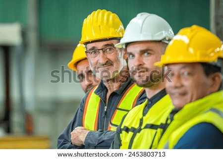 Group of happy workers wearing hard hats and safety vests in a factory