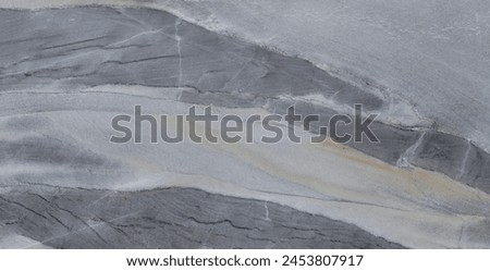 Close-up view of a marble texture with stripes of gray, white, and sandy beige, showing natural veins and subtle color variations.