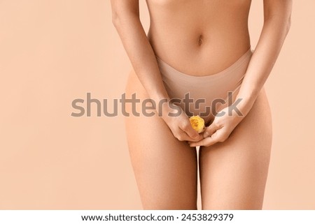 Beautiful young woman in panties with rose flower on beige background, closeup Royalty-Free Stock Photo #2453829379