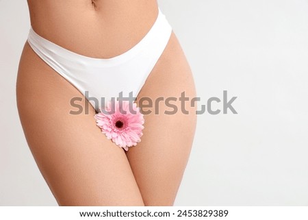 Beautiful young woman in panties with gerbera flower on white background, closeup Royalty-Free Stock Photo #2453829389