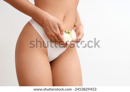 Beautiful young woman in panties with carnation flowers on white background, closeup Royalty-Free Stock Photo #2453829453