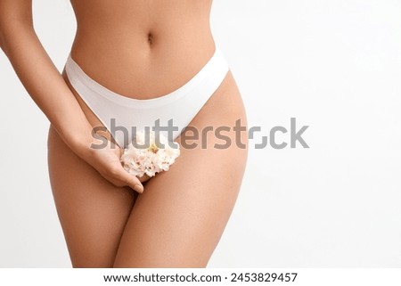 Beautiful young woman in panties with carnation flowers on white background, closeup Royalty-Free Stock Photo #2453829457