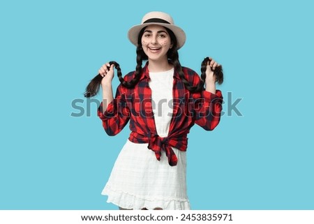 Beautiful young happy woman in wicker hat on blue background. Festa Junina (June Festival) celebration